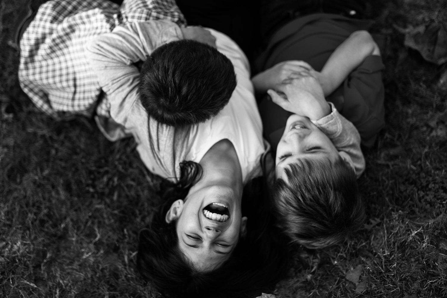 siblings laughing together in grass in Piedmont Park