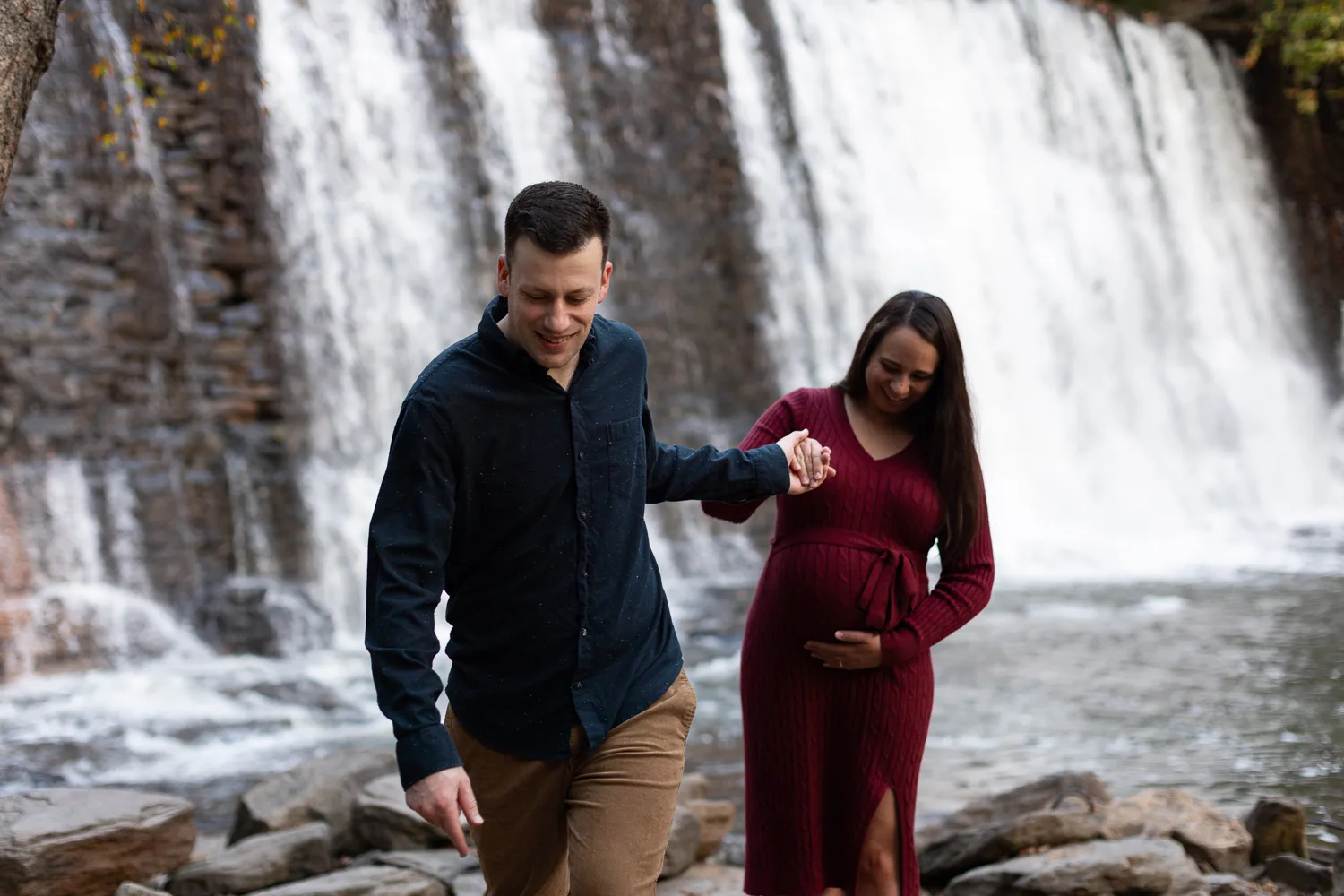 Dad leading pregnant mom away from Roswell Mill waterfall