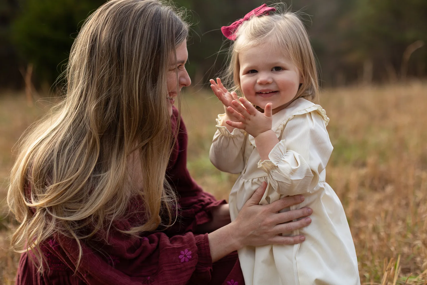Kirsten crouching down to play with Charlotte in a golden field