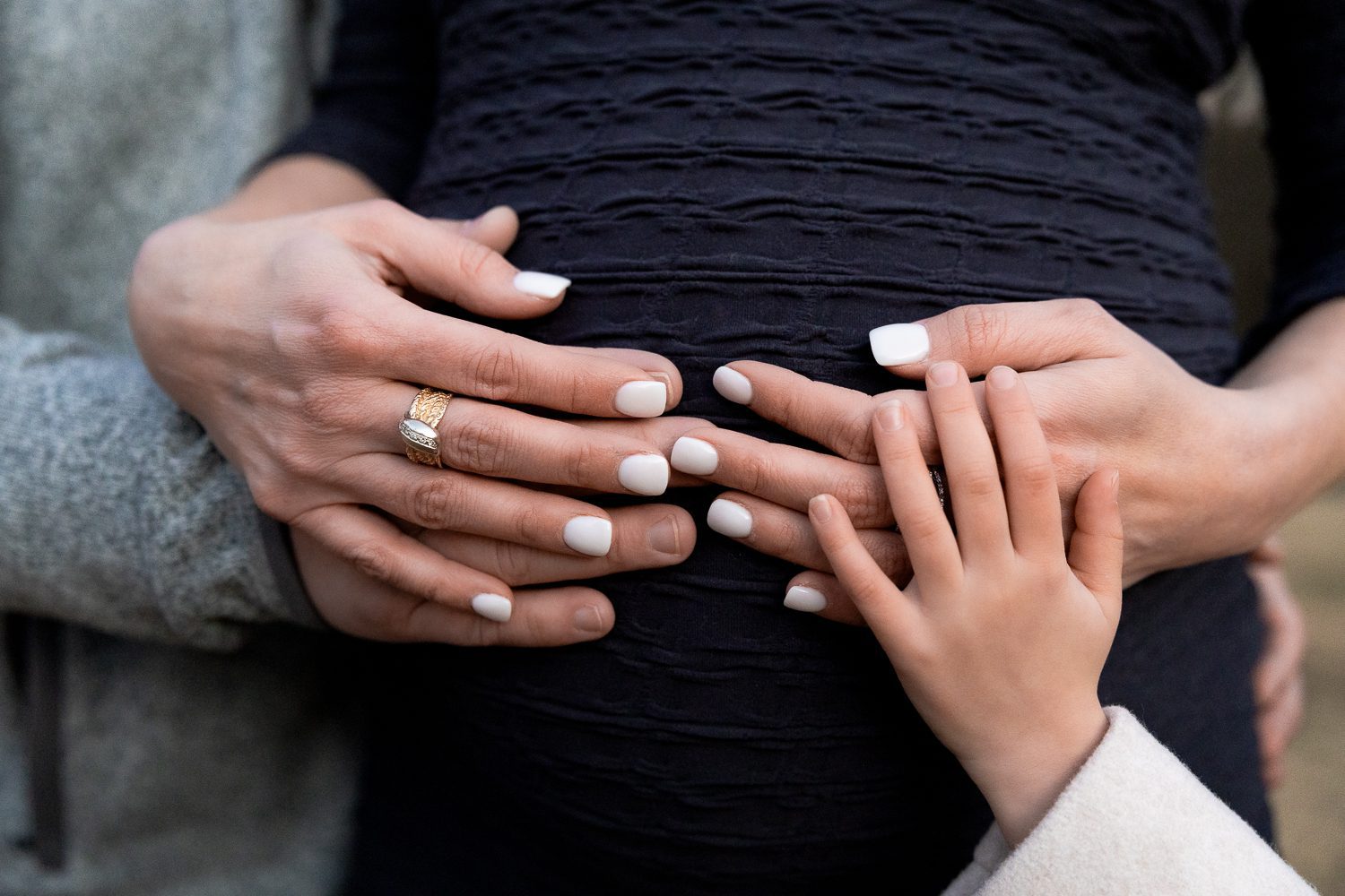 dad and sister's hands on mom's pregnant belly in alpharetta