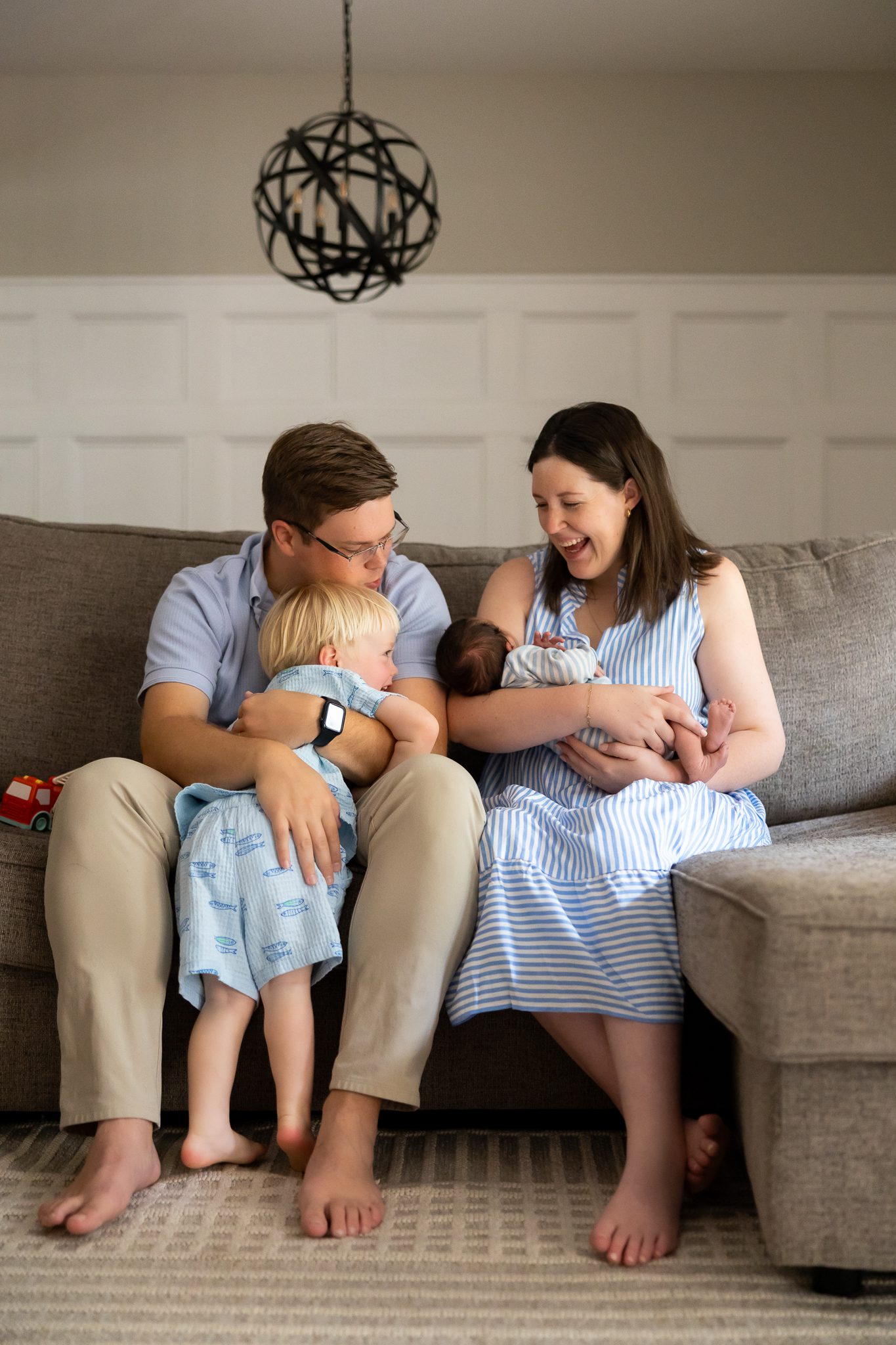 Family of four sitting together on couch during newborn photo session