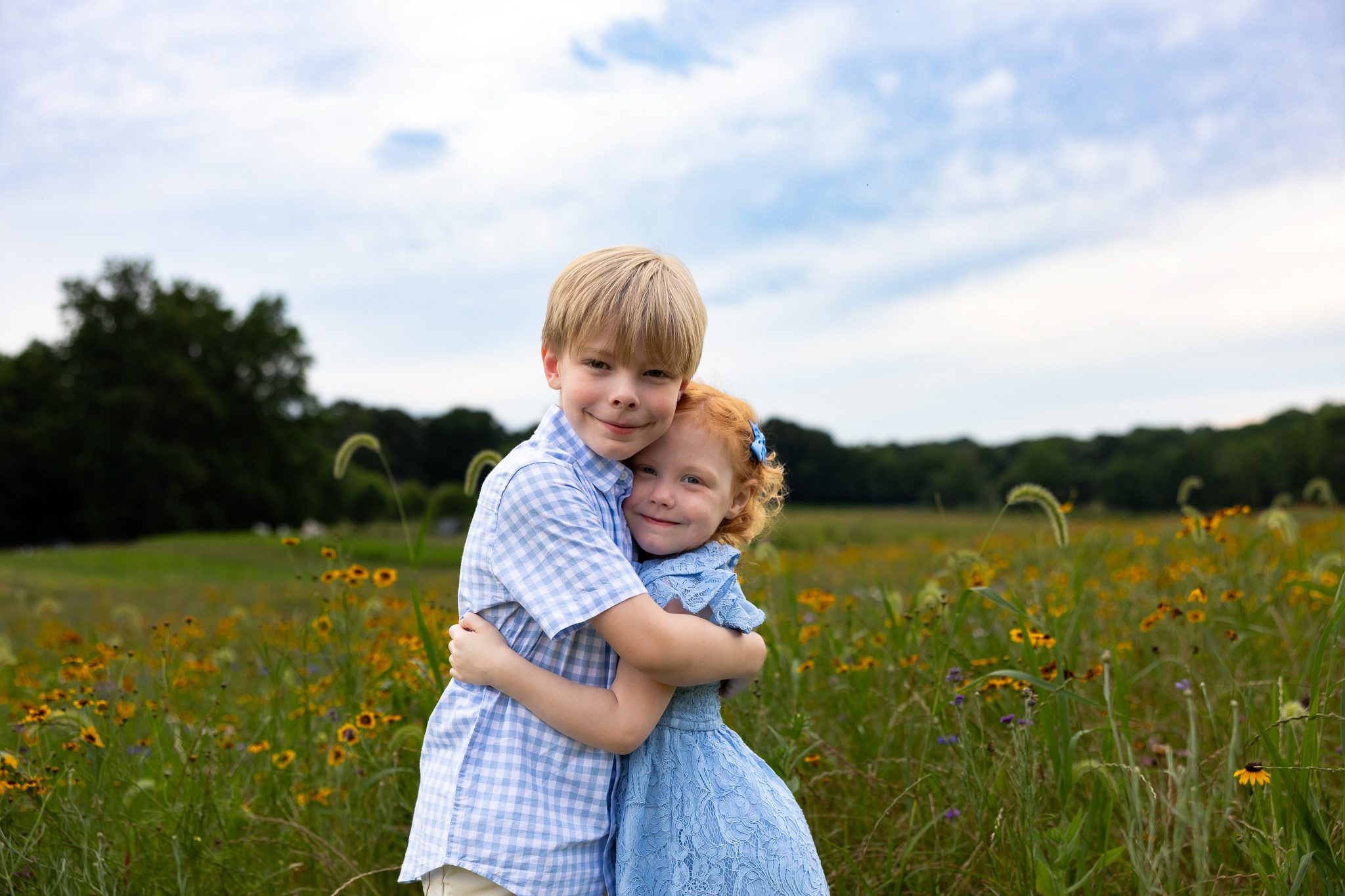 Brother and sister hugging in a flower field during family photos