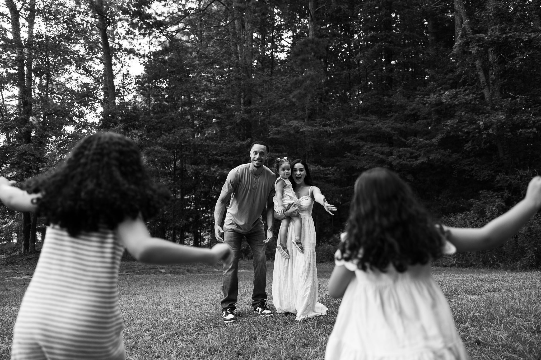 Black and white family photo with sisters running toward parents